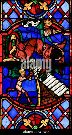 Stained glass window depicting a Devil and an Angel fighting for the soul of a monk in the Cathedral of Tours, France. Stock Photo