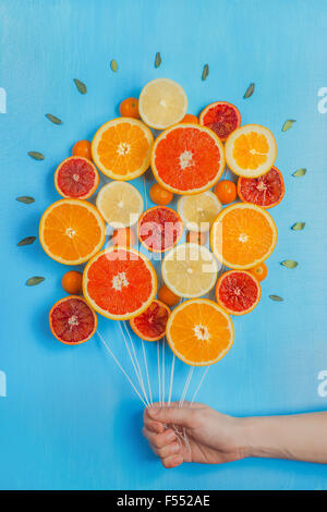 Congratulations on summer! Bouquet of oranges and grapefruits, looking like a bunch of balloons. Sky-blue background. Stock Photo