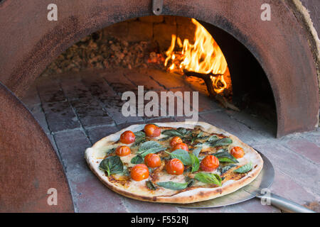 Fresh pizza on peel in traditional oven Stock Photo