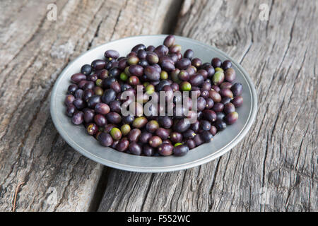 High angle view of purple olives in plate on wood Stock Photo