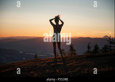 Full length rear view of woman standing on mountain during sunrise Stock Photo