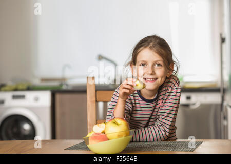 Portrait of happy girl eating apple at table Stock Photo