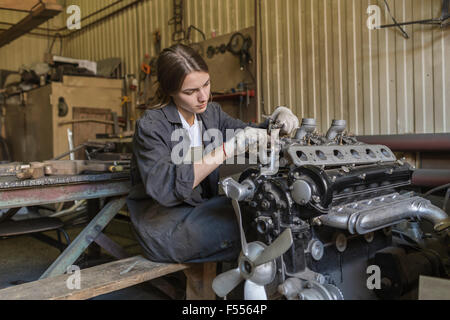 Female mechanic repairing car engine at garage Stock Photo