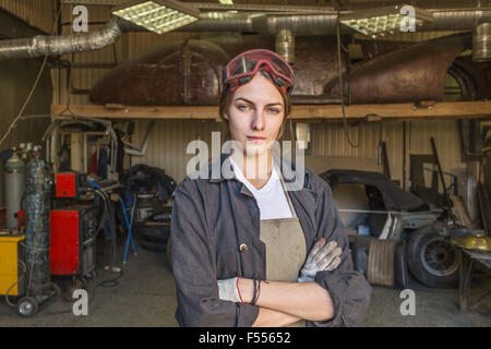Portrait of confident female mechanic with arms crossed at garage Stock Photo