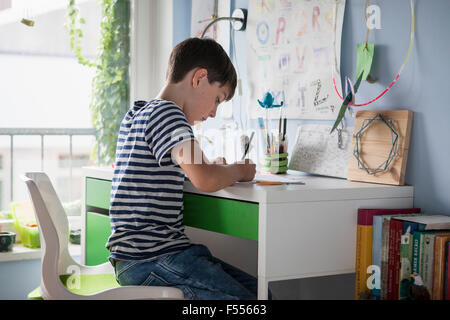 Side view of boy doing homework at table in house Stock Photo