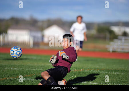 High school keeper makes a big save to on a close in shot to deny a forward a goal late in the match. Stock Photo