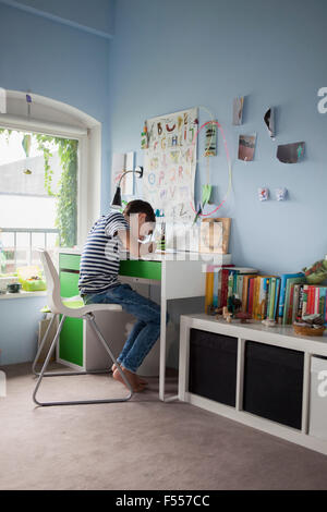 Side view of boy doing homework at table in house Stock Photo