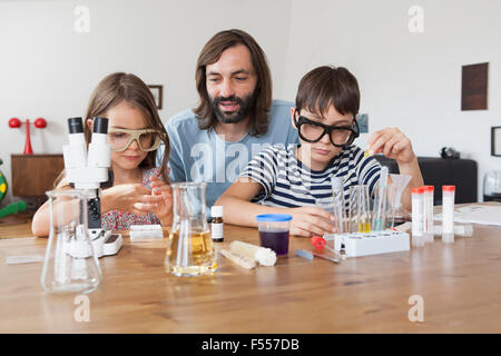 Father assisting children in doing school science project at home Stock Photo