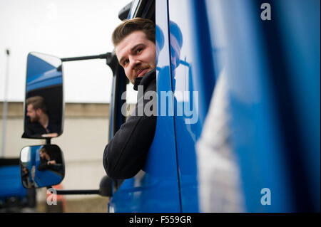 young lorry driver looking in the mirror (MR) Stock Photo
