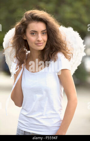 Portrait of smiling woman wearing angel wings outdoors Stock Photo