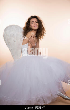 Portrait of smiling bride wearing angel wings against colored background Stock Photo