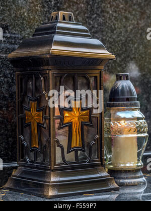 Votive candles lit on black marble tombstone Stock Photo