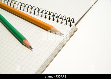 Opened notebook with a blank sheet and pencils on over white Stock Photo