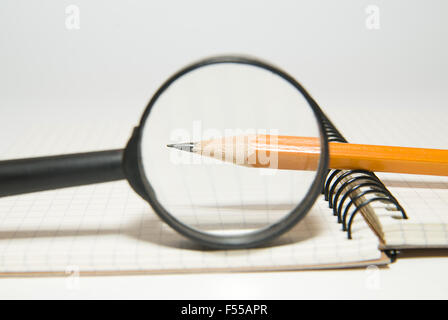 Notepad, pencil and magnifying glass on over white Stock Photo