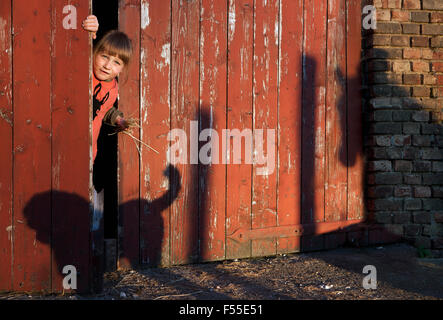 Portrait of girl peeking through barn door Stock Photo