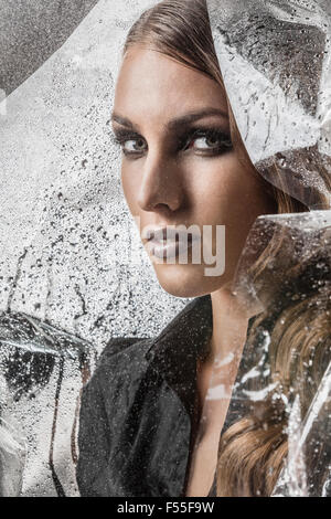 Portrait of beautiful woman wrapped in plastic against black background Stock Photo
