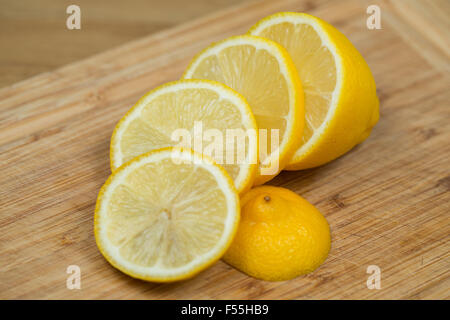 A fresh lemon sliced on a wooden chopping board. Stock Photo