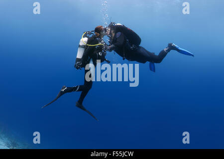 Young couple scuba divers kissing underwater, Indian Ocean, Maldives Stock Photo