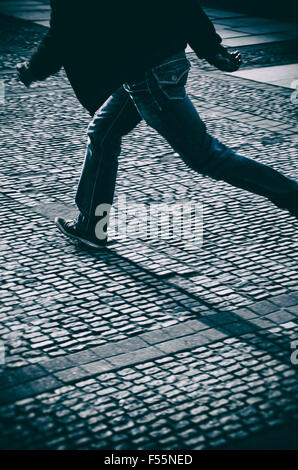 Mysterious man running on a cobbled street Stock Photo