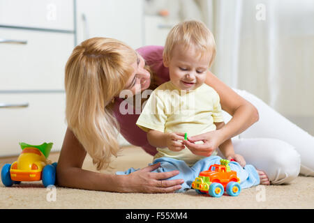 kid boy and his mother repair toy car at home Stock Photo