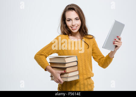 Portrait of a smiling young woman holding paper books and tablet computer isolated on a white background Stock Photo