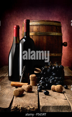 Bottles of wine, corks, corkscrew and wooden cask on table Stock Photo