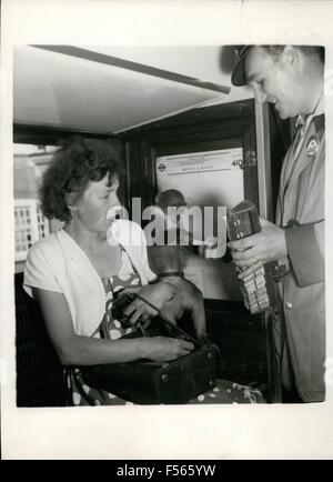 1968 - A Monkey Goes To Work By Bus.: Mickey, the Rhesus monkey, aged one year, is well-known in Biggin Hill, and on the bus route into Woolwich, where his mistress, Mrs. W. Goodsall works in a factory canteen. Every working day, Mickey gets up at the same time as his ''mother'', and after saying hello to his pal, the dog, the cat and the neighboring children, he is groomed, helps to feed the hens, and then sets off to work with her.He rides the first part of the walk to the bus on the back of the big mongrel dog, and then walks a way, but usually ends up in Mrs. Goodsall's grip. He likes play Stock Photo