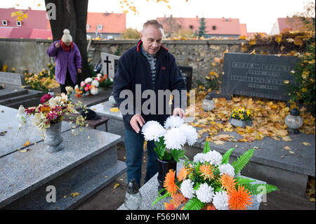 Wielun, Poland. 28th October, 2015. Man makes flower arrangement on the grave as a part of preparations to celebrate catholic All Saint's Day on 1st of November. Stock Photo