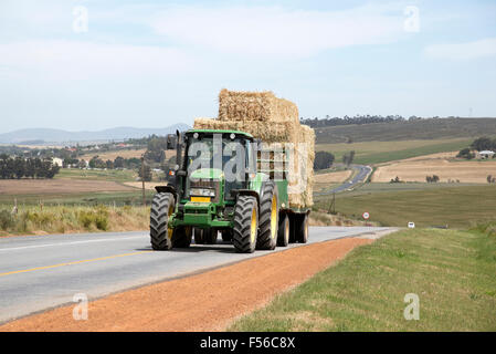 Farm tractor and trailer pulling a load of straw on a public road in the Swartland region of South Africa Stock Photo