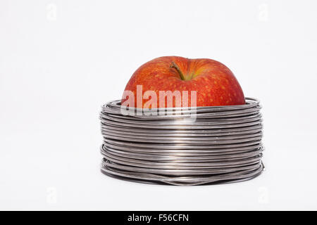 Wired apple: whole red apple in coils of aluminum wire isolated on white background Stock Photo