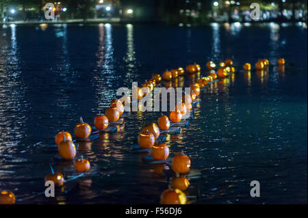 Illuminated carved pumpkins are towed across the Harlem Meer for the Central Park Pumpkin Flotilla in New York on Sunday, October 25, 2015. Prior to Halloween the pumpkins set sail at dusk, towed on their pumpkin rafts by a kayaker, and travel around the Harlem Meer prior to Halloween. thousands of parents and children turn out for the flotilla and  other activities. (© Richard B. Levine) Stock Photo