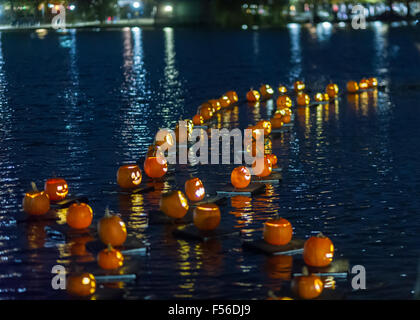 Illuminated carved pumpkins are towed across the Harlem Meer for the Central Park Pumpkin Flotilla in New York on Sunday, October 25, 2015. Prior to Halloween the pumpkins set sail at dusk, towed on their pumpkin rafts by a kayaker, and travel around the Harlem Meer prior to Halloween. thousands of parents and children turn out for the flotilla and  other activities. (© Richard B. Levine) Stock Photo