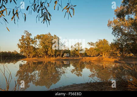 Paroo River with motorhome among trees & blue sky reflected in calm water at Currawinya National Park, outback Australia Stock Photo