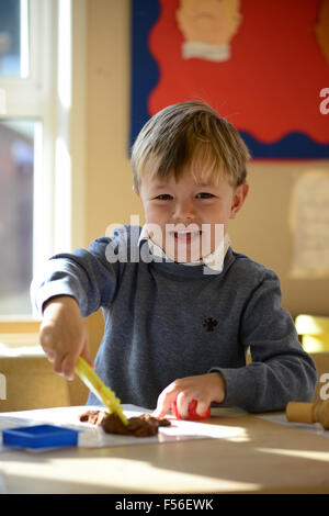 A little boy playing with modelling clay at nursery school. Stock Photo