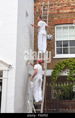 House being painted white by two painters, London England United Kingdom UK Stock Photo