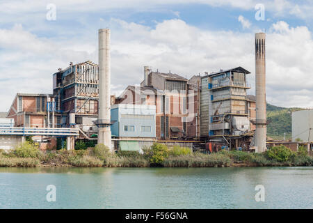 The old chemical factory with chimneys and silo on the banks of the river Stock Photo