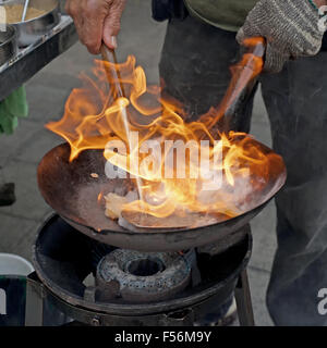 chef cooking with fire in frying pan at outdoor kitchen Stock Photo
