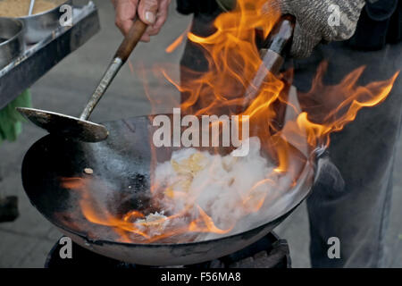 chef cooking with fire in frying pan at outdoor kitchen Stock Photo