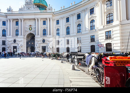 VIENNA, AUSTRIA - OCTOBER 1, 2015: tourists and carriages on Michaelerplatz square of Hofburg Palace. Michaelertrakt was complet Stock Photo