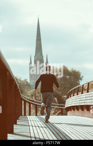 Man running across urban bridge with church in the background Stock Photo