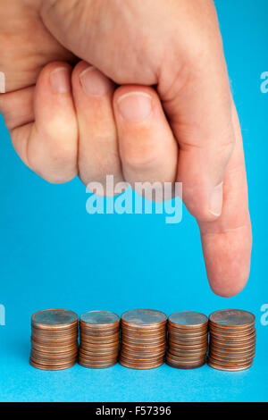 Hand pointing at Euro cent coins in one cent and two cents denominations on blue background. Stock Photo