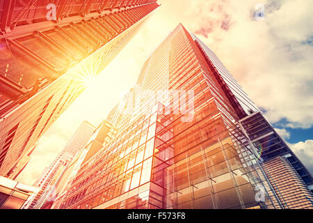 Vintage toned sunset over skyscrapers, modern business background with flare effect. Stock Photo
