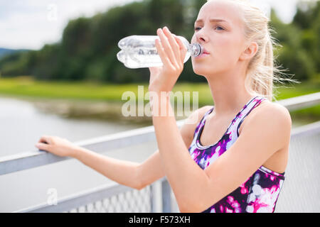 Woman having a break and drinks water after running Stock Photo