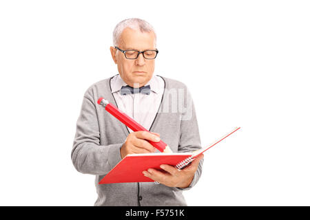 Studio shot of a mature teacher writing something in a notebook with a huge red pencil isolated on white background Stock Photo