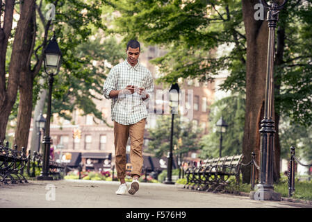 A man walking through a town square looking at his smart phone Stock Photo