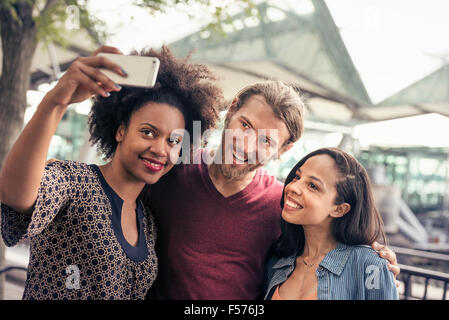 Three people, a man and two women, taking selfies in the park Stock Photo