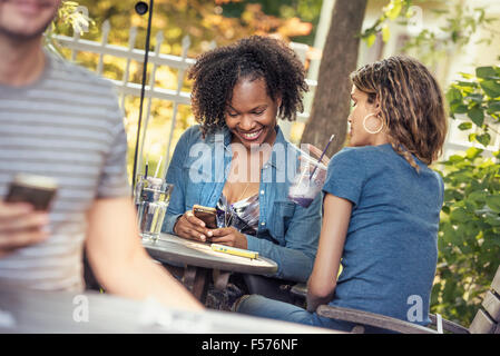 Three people in a cafe diner, two checking their smart phones, Stock Photo