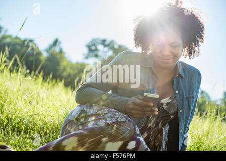 A woman sitting outdoors checking her smart phone. Stock Photo