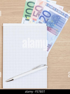 Various euro notes next to notepad on desk Stock Photo