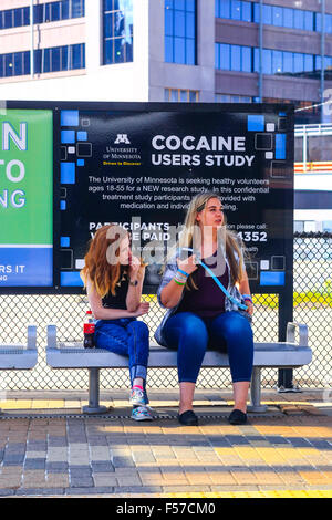 Two young women sit on a Metro platform seat waiting for the next tram in Minneapolis Stock Photo